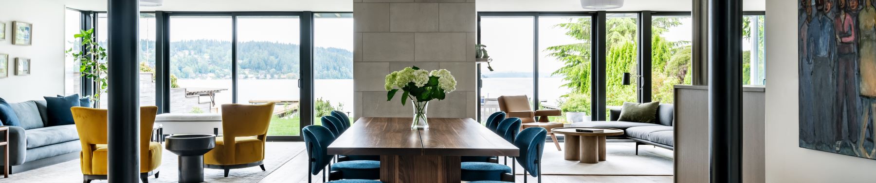 A spacious dining room featuring a large table and chairs, complemented by black Andersen gliding patio doors.